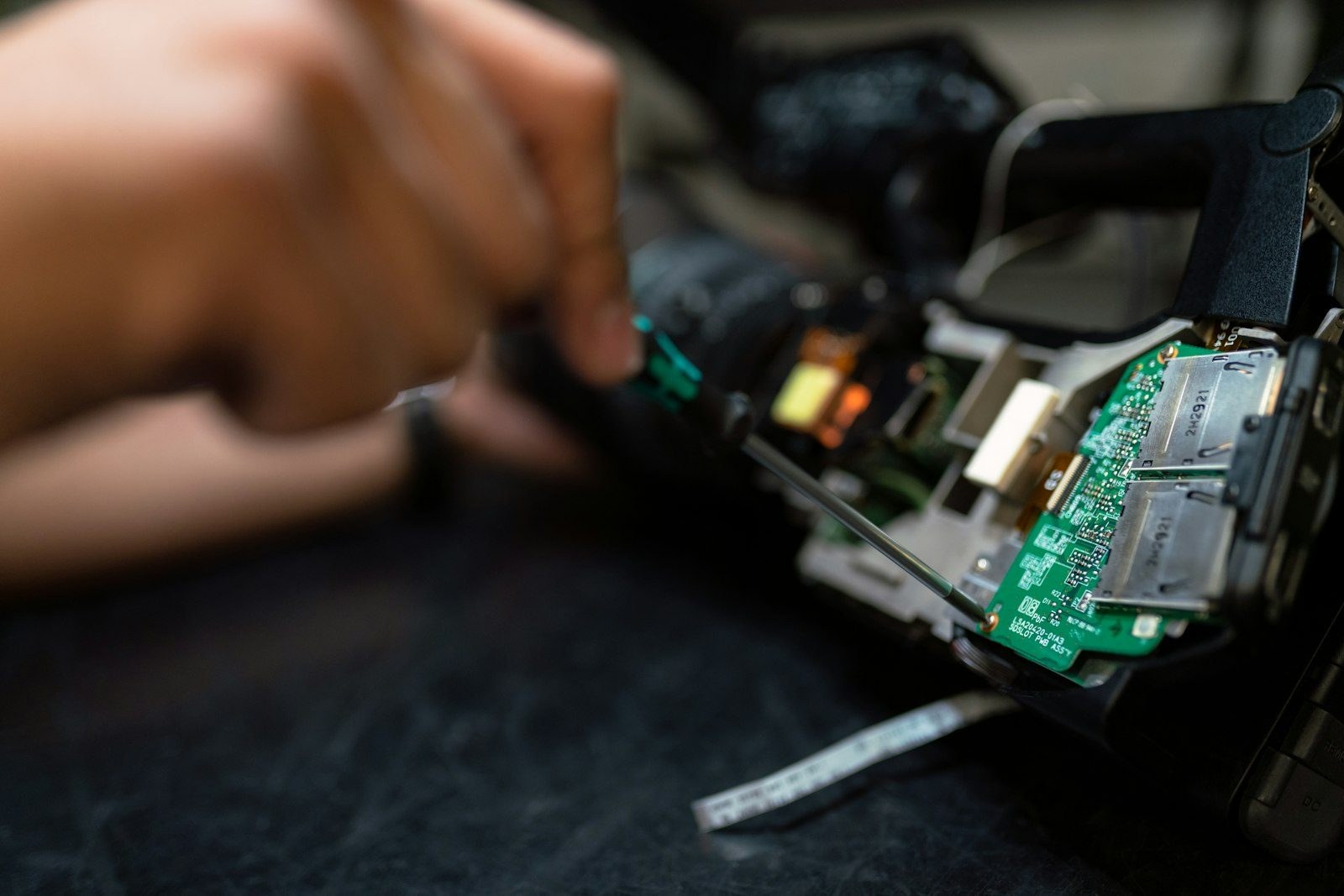 A hand working on a precision component assembly at close range